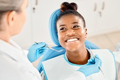 Woman smiling at dentist who is examining her teeth