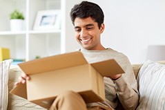 Man in neutral sweater smiling at opened cardboard box