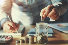 Someone putting coins in a jar