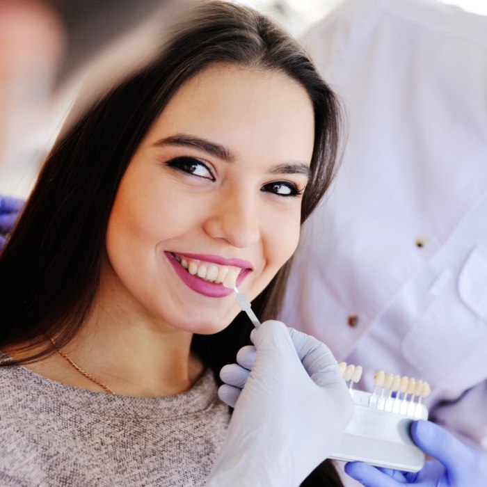 Dentist holding a veneer to a smiling patient