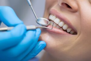 Nose-to-chin profile view of a woman having her teeth examined with dental instruments